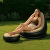 A woman relaxing on an inflatable chair with a footrest in a garden. Produktbild-Vorschau