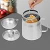 A hand is shown holding a frying basket with fried food inside, over a stainless steel pot. Podgląd zdjęcia produktu