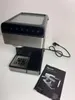 A coffee machine and its instruction manual are placed on a white surface. Anteprima dell’immagine prodotto