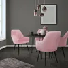 A dining set with pink velvet chairs around a black table, with a framed artwork on the wall. Produktbild-Vorschau
