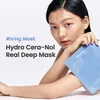 A woman is holding a face mask package. Produktbild-Vorschau