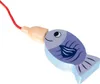 A close-up of a wooden toy fish attached to a red string and a tan bead. Náhled obrázku produktu