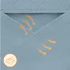 A close-up view of a light blue fabric with orange arrows indicating airflow, suggesting breathability. A small circular icon with a feather is also visible. Náhled obrázku produktu