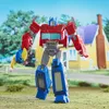A toy robot standing in a grassy yard with a house in the background. Produktbild-Vorschau