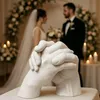 A wedding scene with a couple in the background and a hand cast sculpture in the foreground. Náhled obrázku produktu