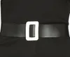 A close-up of a black belt with a white buckle on a black garment. Produktbild-Vorschau