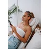 A woman is relaxing on a massage mat while using her phone. Produktbild-Vorschau