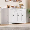 A white sideboard with drawers and doors is shown in a room with a rug and a plant. Voir les images du produit