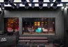 A dimly lit lounge area with modern seating and decorative wall panels, featuring a DJ setup and a Red Bull logo. Produktbild-Vorschau