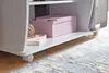 A close-up view of a white computer desk with a pink box, a book, and a ball of twine on a shelf. The desk has wheels. Podgląd zdjęcia produktu