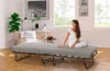 A woman sitting on a folding bed in a room. Produktbild-Vorschau