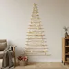 A wall-mounted Christmas tree decoration made of wooden branches, adorned with fairy lights, in a cozy living room setting. Podgląd zdjęcia produktu