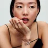 A close-up shot of a woman's hand and arm adorned with Pandora jewelry, including rings and a charm bracelet. Produktbild-Vorschau