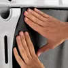 Hands applying a dark gray foam material to a white surface. Produktbild-Vorschau