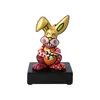 A colorful ceramic figurine of a rabbit holding an egg, placed on a black base. Produktbild-Vorschau