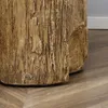 A close-up view of the base of a faux tree stump side table, showing its textured surface and a small logo. Produktbild-Vorschau
