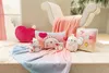 A collection of plush toys and blankets arranged on a wooden surface in front of a chair. Produktbild-Vorschau