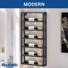 A modern black metal wine rack mounted on a wall, holding six bottles of wine. The rack is positioned next to a white curtained window, with a piece of abstract art on the wall to the right. The word 'MODERN' is displayed prominently at the top of the imag Náhľad obrázku produktu