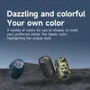 Three portable Bluetooth speakers in different colors are displayed on a rocky surface against a dark blue background. Produktbild-Vorschau