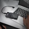 A person's hand is typing on a laptop keyboard, with an external SSD connected to the laptop. Voir les images du produit