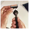 Hands holding a razor and a replacement blade. Produktbild-Vorschau