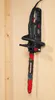 A black electric chainsaw is mounted on a light brown wooden wall. Produktbild-Vorschau