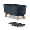 A dark gray planter with wooden legs and a black tray underneath, isolated on a white background. Podgląd zdjęcia produktu
