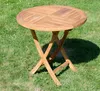 A round wooden folding table is shown outdoors on a grassy lawn. Produktbild-Vorschau