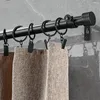 A close-up view of a black curtain rod with rings and clips holding up beige curtains against a gray tiled wall. Produktbild-Vorschau