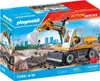 The image shows the packaging of a Playmobil Action Heroes excavator toy set. The packaging features a scene of the excavator in action on a construction site, with buildings in the background. The product itself is prominently displayed on the front of th Náhled obrázku produktu