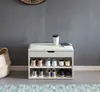 A shoe bench with storage and a padded seat, placed against a gray wall with a woven basket to the side. Produktbild-Vorschau