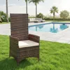 A brown rattan chair with a beige cushion is placed on a green lawn next to a swimming pool. Produktbild-Vorschau