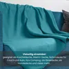 A turquoise fleece blanket draped over a blue sofa. Náhled obrázku produktu