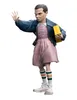 A figurine of Eleven from Stranger Things, holding a yellow box and raising her hand. Náhled obrázku produktu