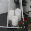 Three white LED candles are placed inside a white lantern, surrounded by small stones and a red rose. Produktbild-Vorschau