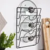 A black metal pot lid organizer mounted on a white wall, holding three glass pot lids. Produktbild-Vorschau