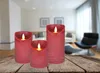 Three red LED candles with flickering flames are placed on a wooden table in a blurred living room setting. Podgląd zdjęcia produktu