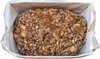 A loaf of bread covered in seeds and grains, placed inside a baking pan lined with parchment paper. Produktbild-Vorschau