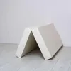 A folded mat leaning against a white wall on a light wooden floor. Anteprima dell’immagine prodotto
