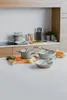 A collection of cookware and kitchen utensils arranged on a countertop, with some vegetables and a butternut squash. Anteprima dell’immagine prodotto