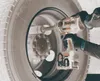 A person is using a Makita cordless impact wrench to tighten lug nuts on a large vehicle wheel. Produktbild-Vorschau