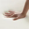 A hand pressing into a soft, beige surface. Produktbild-Vorschau