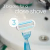 A close-up of a blue and white razor head with three blades, positioned in front of a white sink. Anteprima dell’immagine prodotto