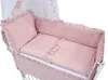 A close-up view of a pink baby crib with bedding. Produktbild-Vorschau