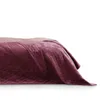 A close-up side view of a quilted bedspread draped over a bed. Produktbild-Vorschau