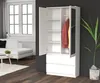A white wardrobe with its doors open, revealing shelves and hanging clothes, stands in a room with a sofa and window in the background. Produktbild-Vorschau