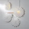 Four white paper star decorations hanging on a white wooden wall. Podgląd zdjęcia produktu
