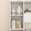 A white shelf unit with decorative figures and books. Podgląd zdjęcia produktu