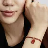 A close-up shot of a woman's wrist wearing a Pandora charm bracelet with a red horse charm. Produktbild-Vorschau