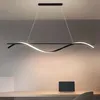 A modern LED pendant light fixture with a wavy design is suspended over a desk with a laptop. Produktbild-Vorschau